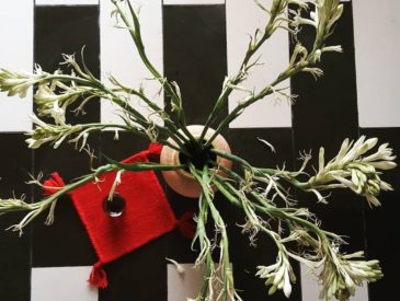 A picture of fresh flowers in earthen pot on black and white floor.