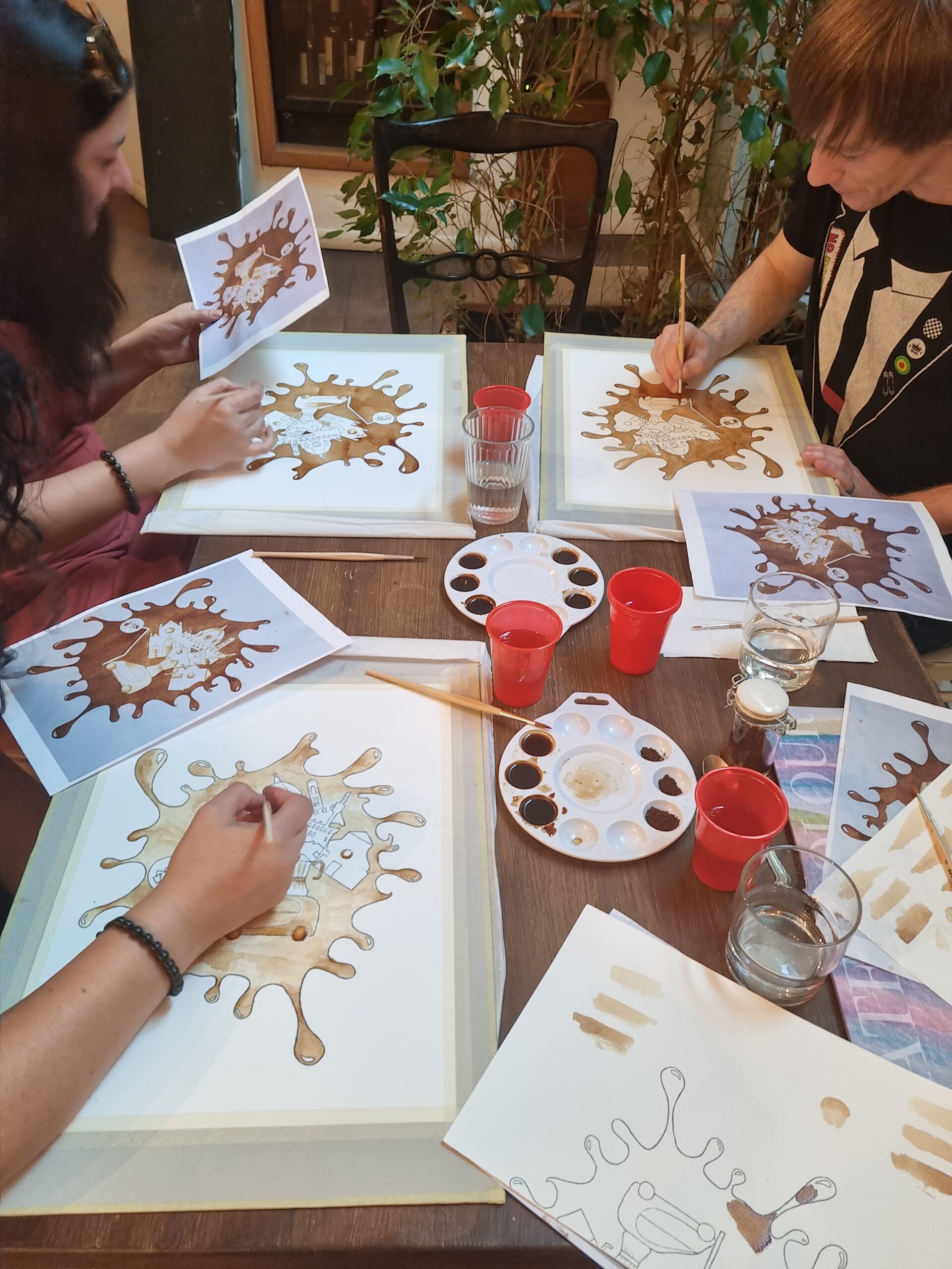 A group of young adults painting with coffee.