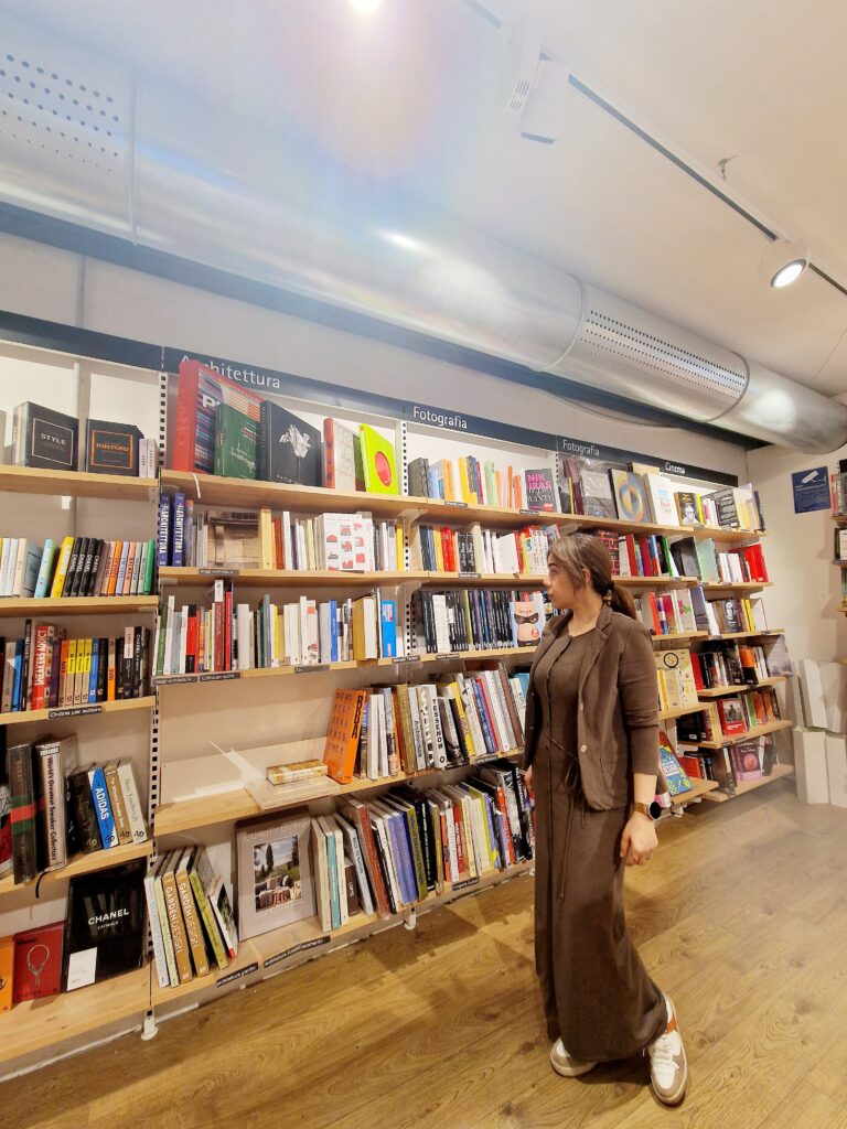 Picture of a girl standing in front of a bookshelf in a bookstore. 