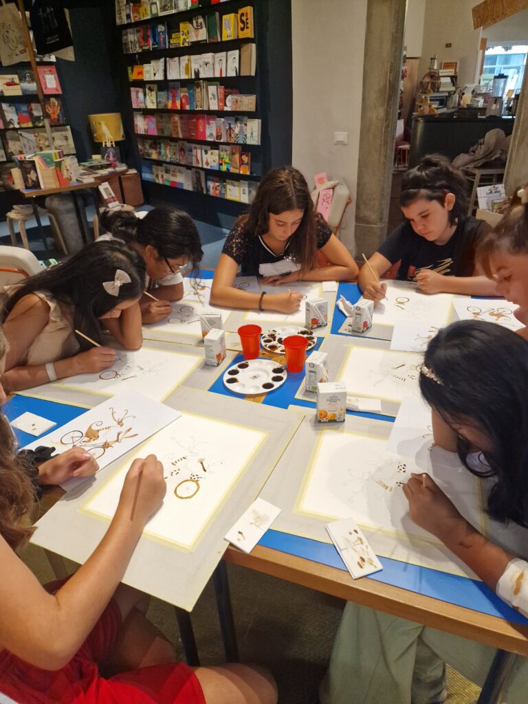 A group of kids sitting at a table for an art event. 