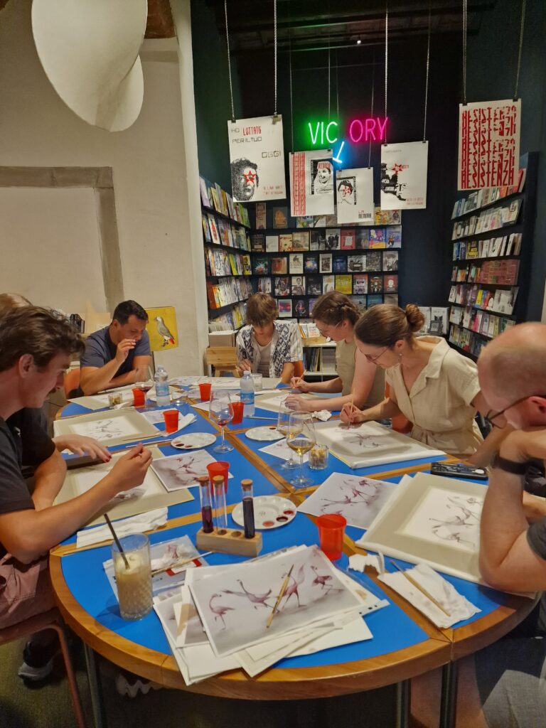 A big group of men and women sitting at a table for Sip & Dip Painting with Coffee event.